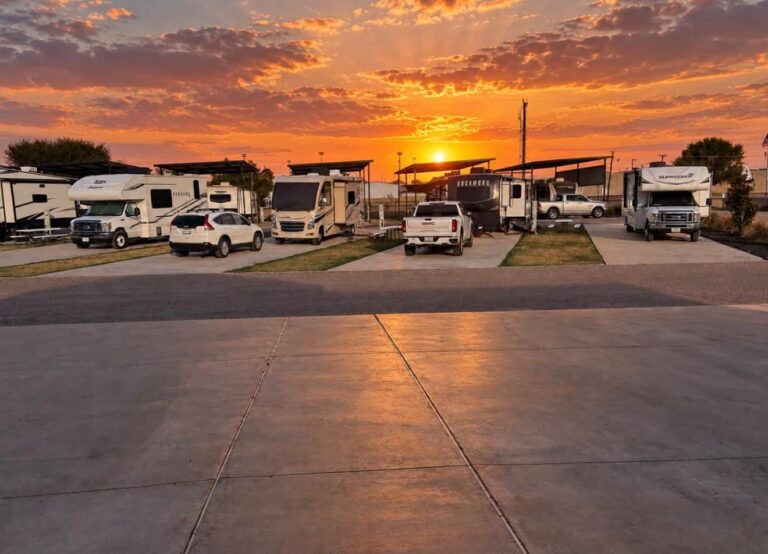 Motorhomes and travel trailers parked on concrete RV sites at Magnolia RV Resort at sunset
