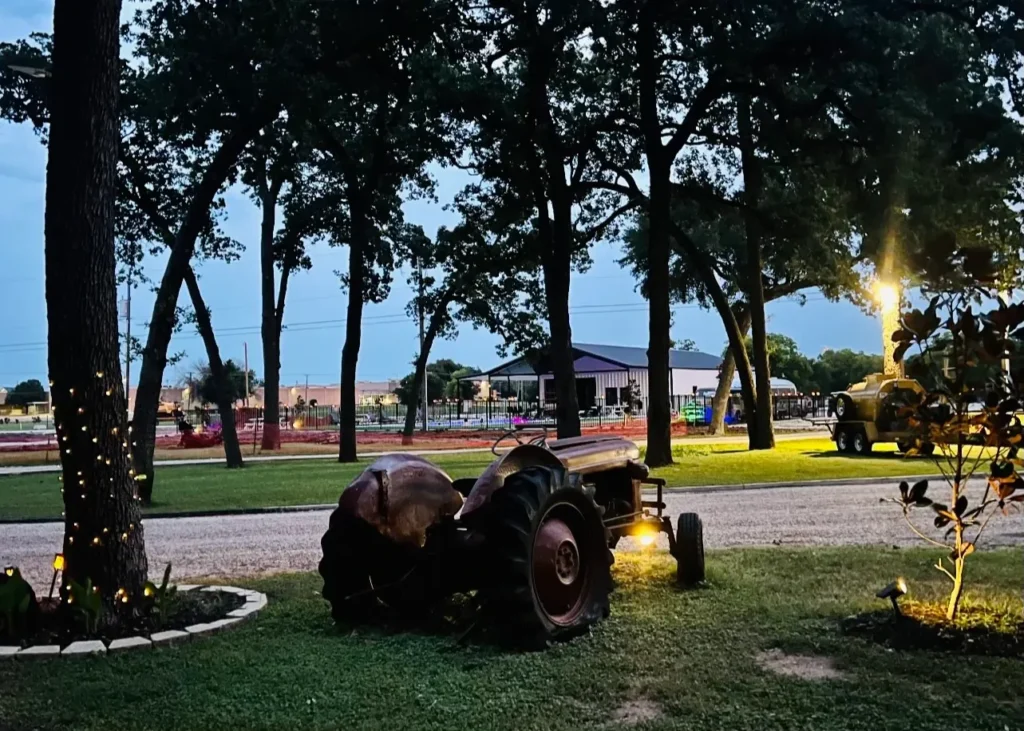 Shaded grounds with a vintage tractor at Magnolia RV Resort in Waco, Texas