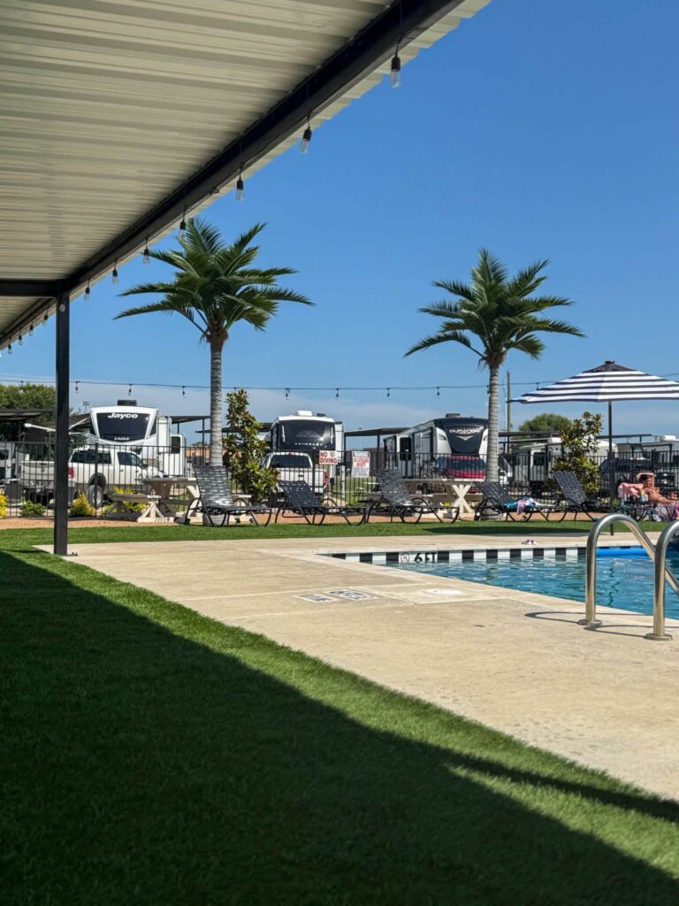 Pool deck with palm trees at Magnolia RV Resort