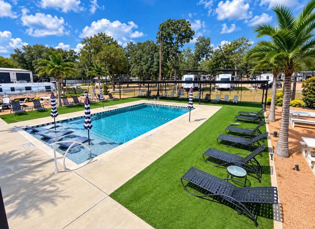Pool with loungers and palm trees at Magnolia RV Resort in Waco